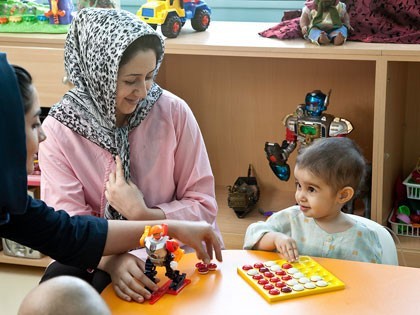 MAHAK child with psychologist in the play room The child learning how to play with the help of psychologist and enjoying her mom's company